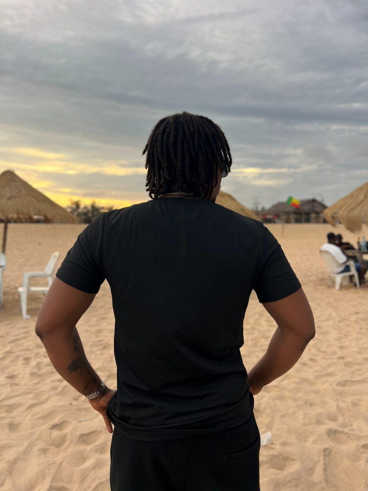 OIM THUG de dos, sur la plage, le drapeau du Bénin au loin