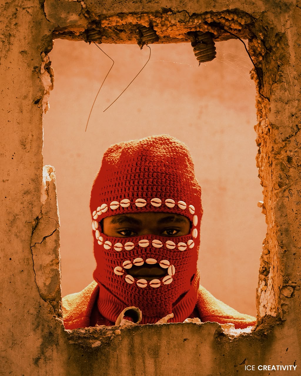 OIM THUG en cagoule rouge, le visage dans l’ouverture d’un mur